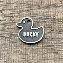 Load image into Gallery viewer, Metal rubber duck-shaped tag with 'DUCKY' text on a wooden surface