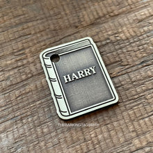 Load image into Gallery viewer, Dog ID tag shaped like a book with the name Harry deep engraved, personalised engraved metal pet tag for book lovers with a classic storybook design.