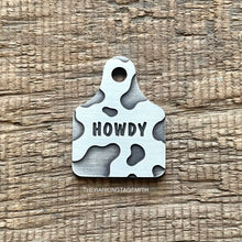 Load image into Gallery viewer, Dog ID tag shaped like a cattle ear tag with cow print pattern and engraved name Garrett, personalised deep engraved metal pet tag.