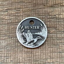 Load image into Gallery viewer, Dog ID tag with duck hunting scene deep engraved on round metal tag, personalised pet tag featuring flying duck, reeds and water design.