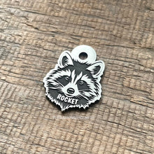 Load image into Gallery viewer, Dog ID tag shaped like a raccoon face with detailed deep engraved raccoon design and the name Rocket, personalised engraved metal pet tag.