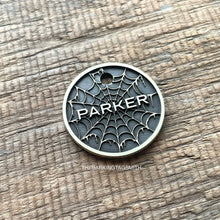 Load image into Gallery viewer, Personalised spider web dog ID tag with engraved gothic web pattern and raised Parker name in brushed silver metal on rustic wood background
