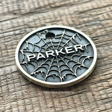 Load image into Gallery viewer, Personalised spider web dog ID tag with engraved gothic web pattern and raised Parker name in brushed silver metal on rustic wood background